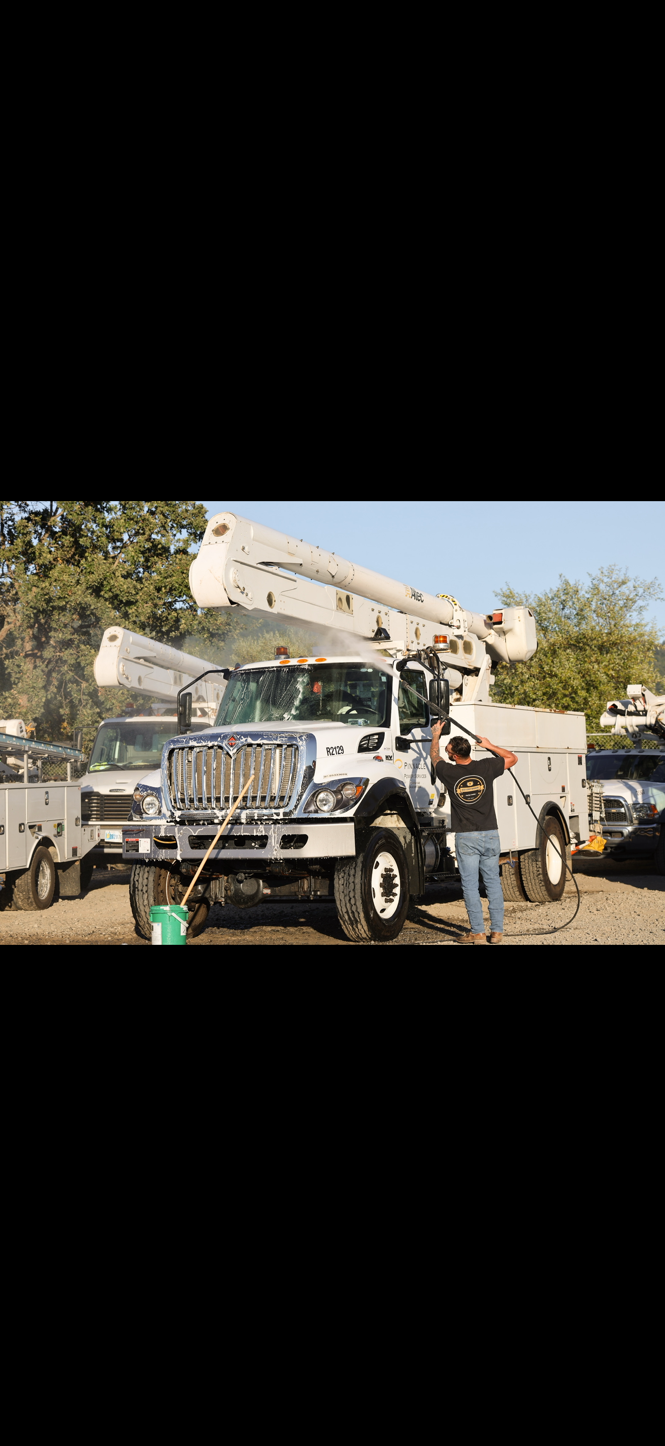Worker washing a utility bucket truck