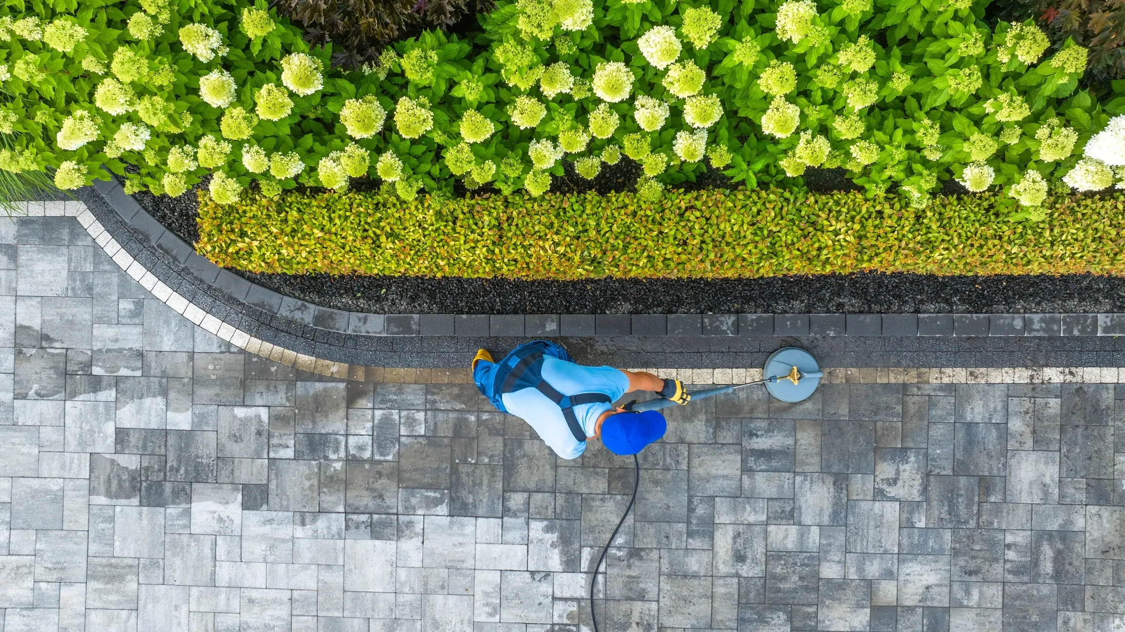 Worker pressure washing a paved residential walkway